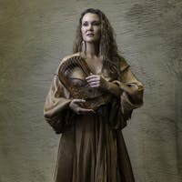 A woman in a brown gown gracefully holds a lyre, exuding artistic elegance.