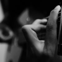 Black and white photo of a guitarist's hands playing an acoustic guitar, emphasizing musical expression.