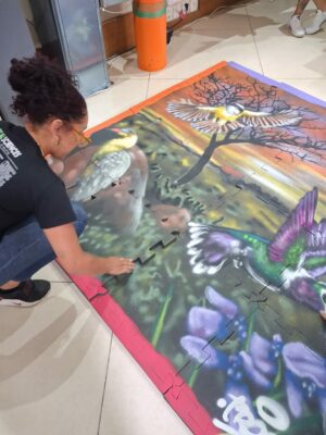 A aluna do curso de biologia, Kétellin, aparece finalizando a montagem do quebra-cabeça no chão inserindo a última peça.