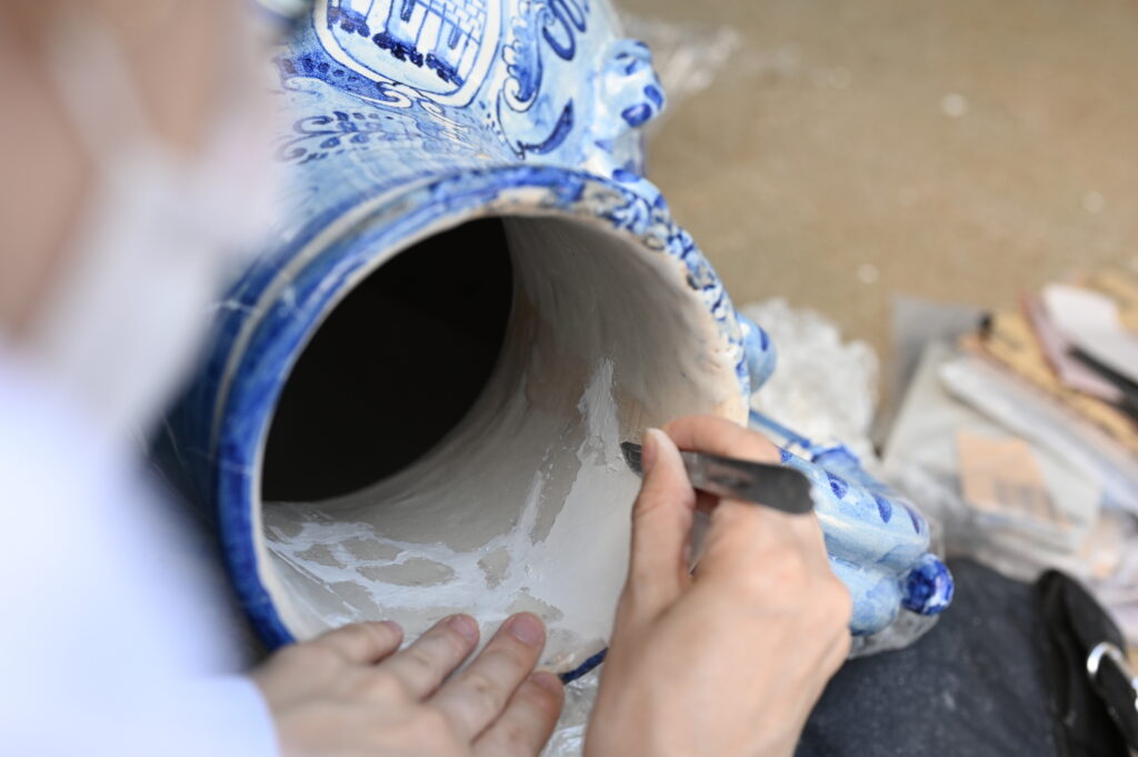 Detalhe do processo de restauração da peça "Idria em Majólica Italiana", conduzido pela equipe do LACORPI no laboratório do Palácio da Alvorada, com foco na conservação de cerâmica histórica.